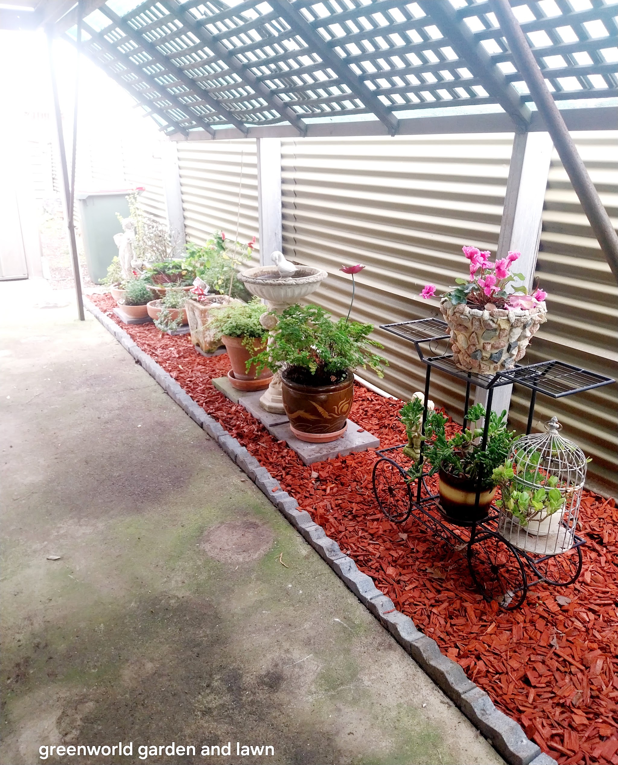 Potted display garden on red bark mulch with stone paver edging